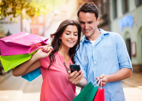 Young couple with shopping bag using mobile phone