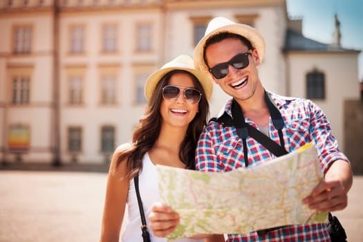 Happy tourists couple holding map