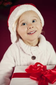 Cute girl with santa hat holding christmas gift