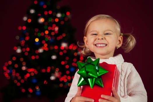 Cute little girl holding christmas gift