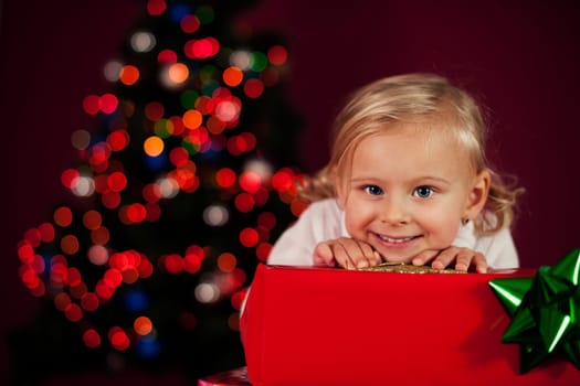 Cute little girl leaning on christmas present