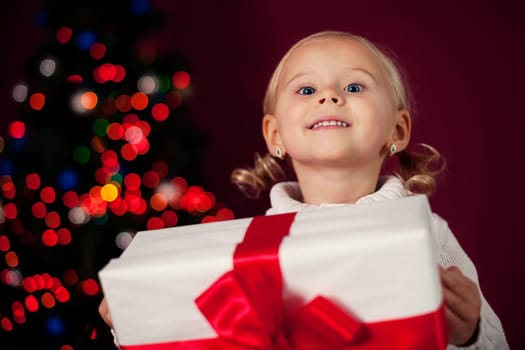 Happy little girl at christmas time holding her present