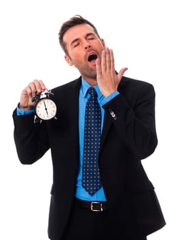 Yawning businessman holding alarm clock