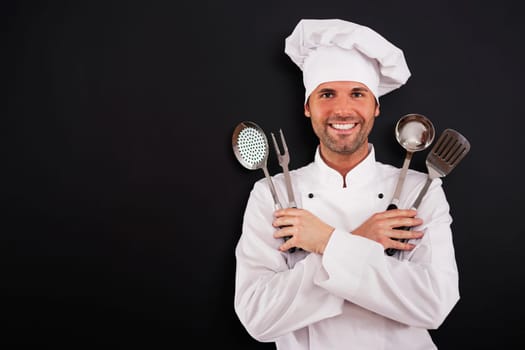 Happy young chef with cooking equipment
