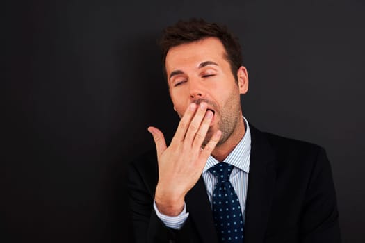Young businessman yawning and covering his mouth