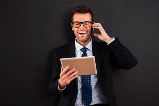 Handsome businessman working with mobile phone and digital tablet