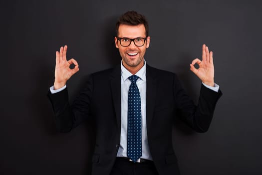 Happy businessman wearing glasses showing OK sign