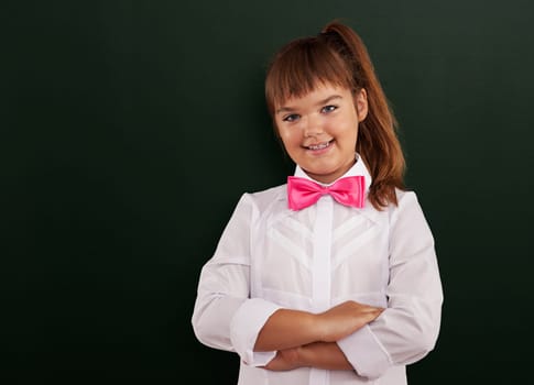 Cute schoolgirl posing in front of blackboard