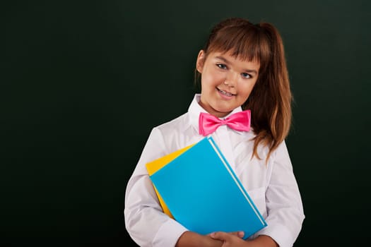 Portrait of cute little schoolgirl with notebooks