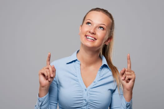 Smiling and beautiful woman showing on copy space above her