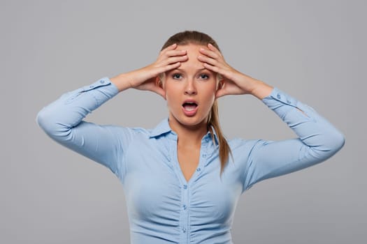 Confused and shocked businesswoman holding hands on head
