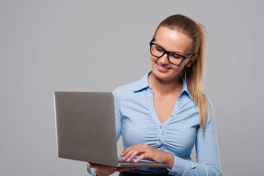 Smiling young businesswoman working on slim laptop
