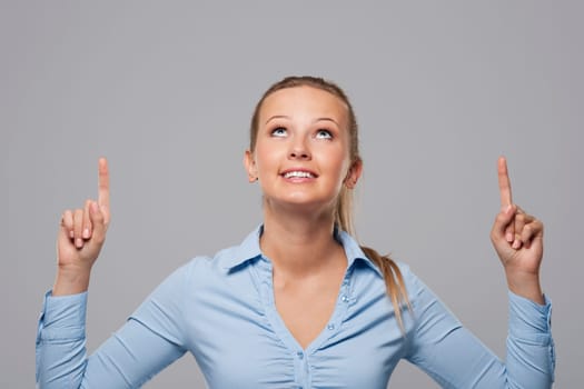 Blonde businesswoman pointing above at copy space