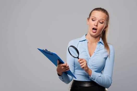 Shocked woman looking at office documents with magnifier