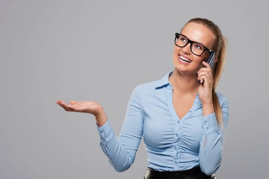 Businesswoman talking on mobile phone and showing on copy space