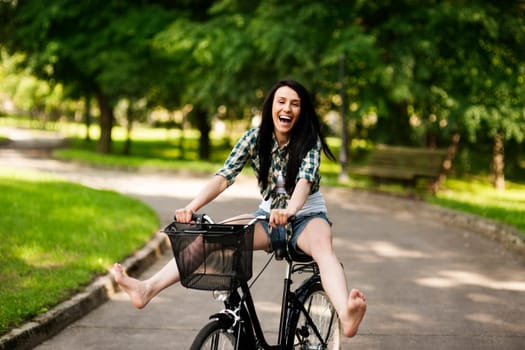 Happy young woman cycling through the park