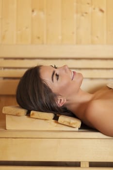 Smiling beautiful woman resting in sauna