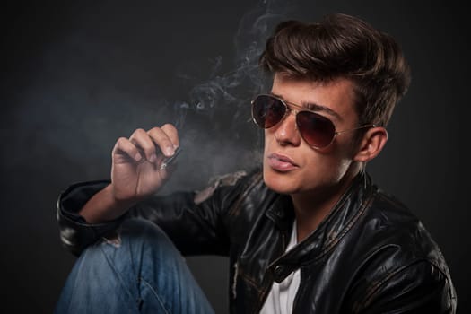 Portrait of young man wearing sunglasses and smoking