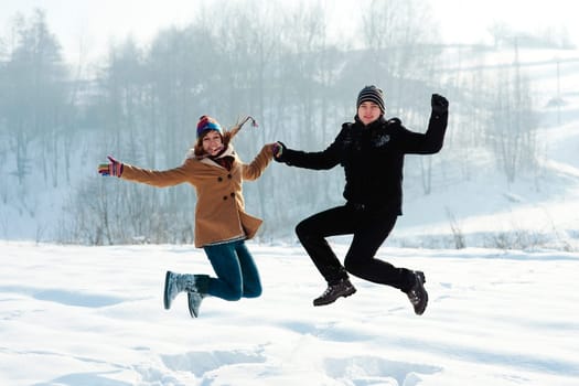 Winter fun, young couple jumping outdoors