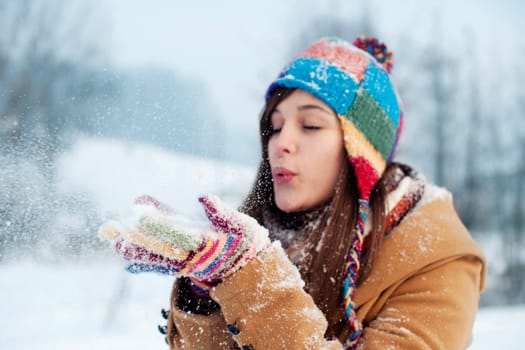 Young woman blowing snow to away