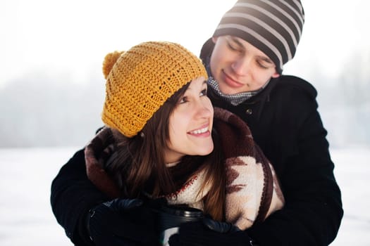 Young man wrapping his girlfriend into blanket
