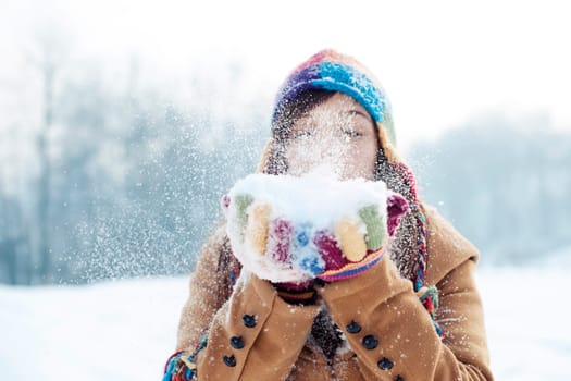 Young woman blowing snow to away