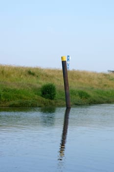 The photograph of a river with a dike and a steel pillar.