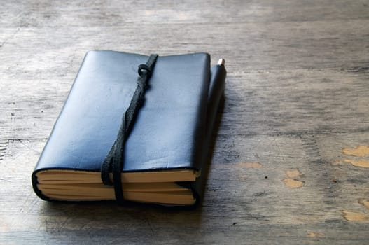 A leather bound journal sits on a table outside with a cord wrapped around the pages to keep place in book.