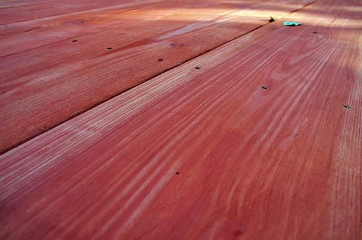 Looking down the length of a red stained wooden picnic table in perspective.