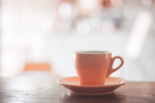 Orange coffee cup on wooden table, stock photo