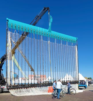 people in front of an industrial fishing net in Urk. Urk has by far the largest fishing fleet and fish processing industry in the Netherlands.