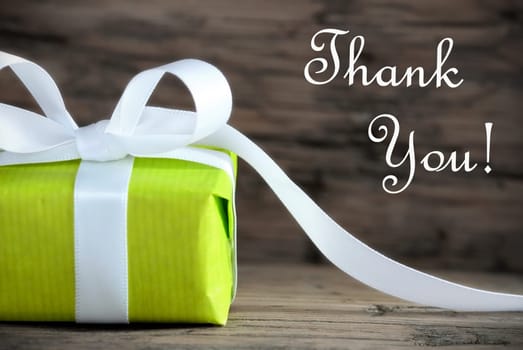 Green Gift with White Ribbon on Wood and the Text Thank You