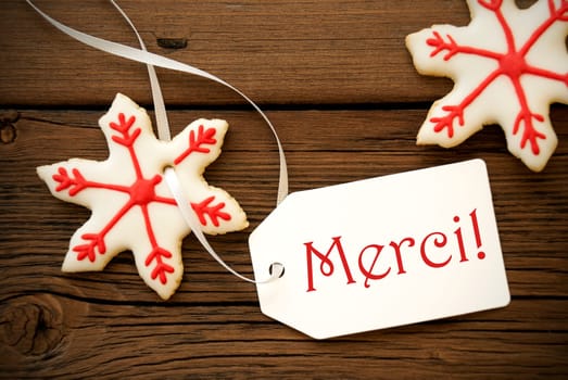 Christmas Star Cookies with red and white Decoration and a Label on which the French Words Merci is written which means Thanks