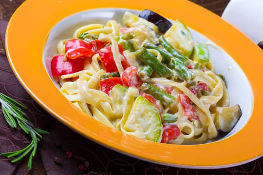 Italian vegetarian pasta with sauce and vegetables, served on a plate