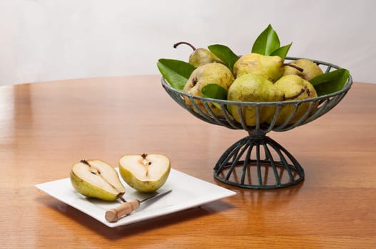 Fresh golden pears in wire basket on a wooden table