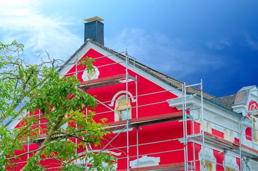 Detail red painted house facade with scaffolding in the background a dark blue sky