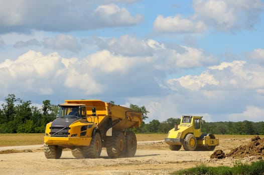 Dump truck and wheel roller on construction site