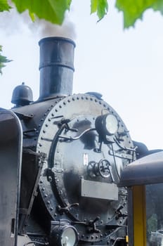 Front view of a steam locomotive under full steam at the entrance to a station.