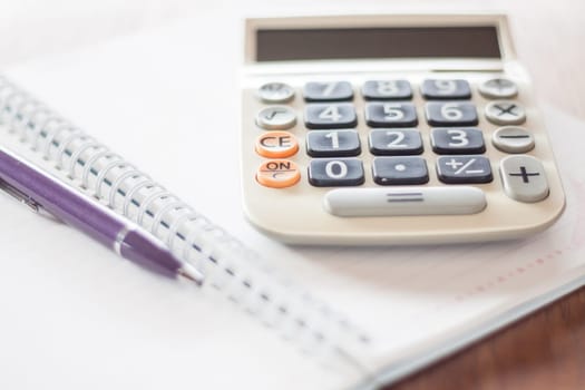 Calculator and pen on notebook, stock photo