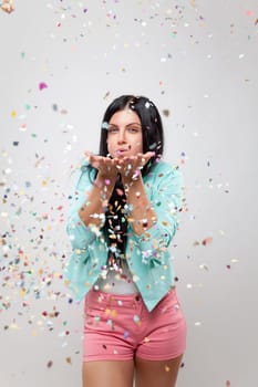 Young beautiful woman in party mood with confetti all around