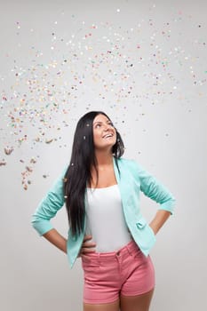 Young beautiful woman in party mood with confetti all around