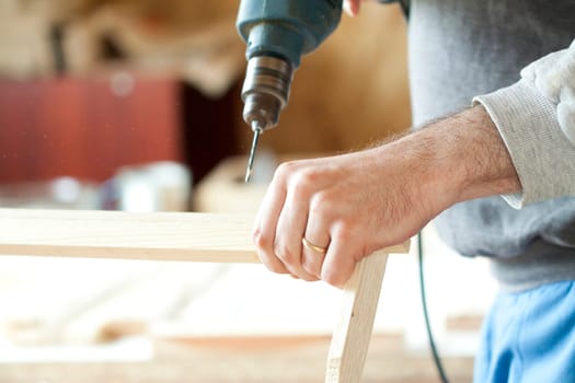 Man's arms drill lath in the workshop.