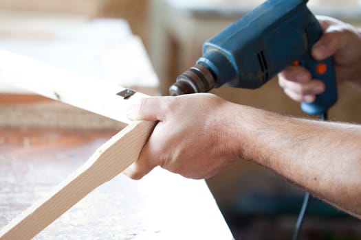 Man's arms drill lath in the workshop.