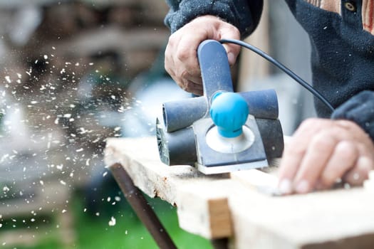 Man's arms sawing wood board in the workshop.