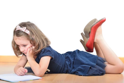 Little cute girl wearing mother's shoes is reading and posing