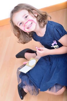 Little cute girl using make-up to turn herself into clown