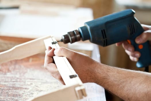 Man's arms drill lath in the workshop.
