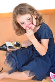 Little cute girl using make-up to turn herself into clown