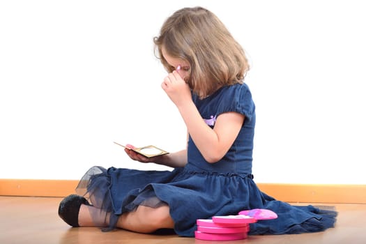 Little cute girl making up while wearing her mother's shoes