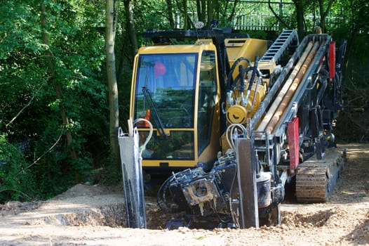 The photograph of an excavator and construction equipment in an earth trench.